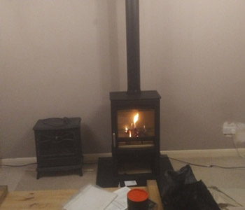 Parkray Aspect 5 wood burning stove - with log store by Hunter Stoves on black polished granite hearth with internal metal factory made chimney system in Bookham, near Leatherhead, Surrey.
